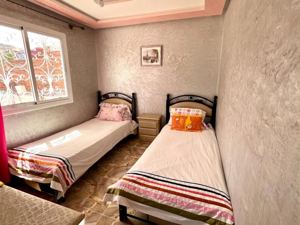 Dos camas individuales en una habitación con ventana. en Maison Parfaite à Chaouen, en Chefchaouen