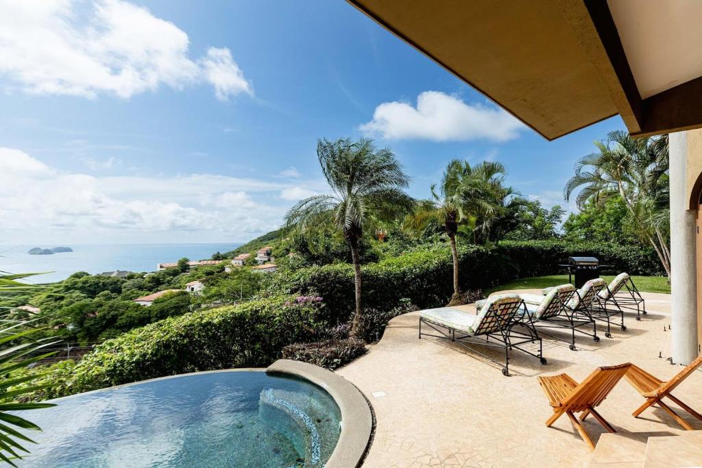 a pool with chairs and the ocean in the background at Dos Vistas in Playa Hermosa