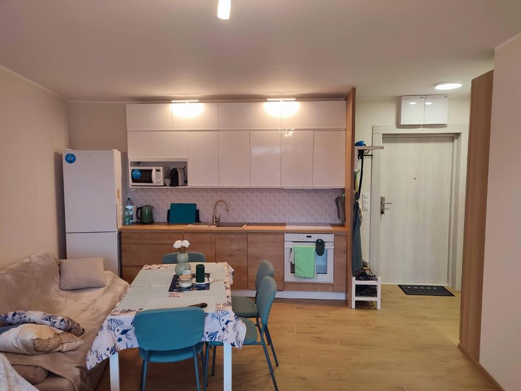 Una sala de estar con una mesa y una cocina. en Apartament Jasny Spokój, en Jantar