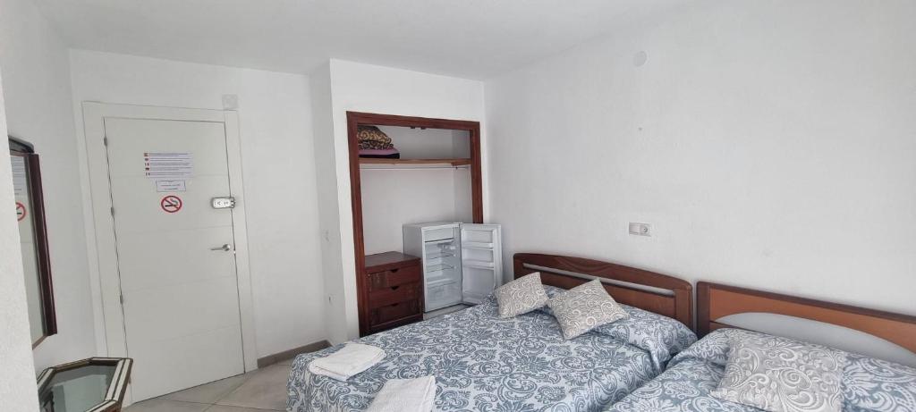 a small bedroom with two beds and a mirror at Habitación Doble con capacidad para Tres a 100 m de la Playa in Benidorm