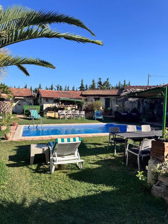 a pool with a table and chairs next to a house at Le petit Olivier 