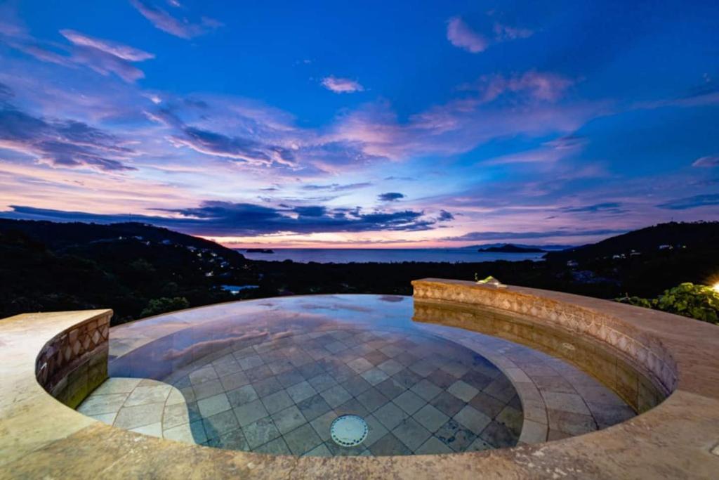 an outdoor pool with a sunset in the background at Casa Texvol 3br Villa W Ocean View Pool in Playa Hermosa