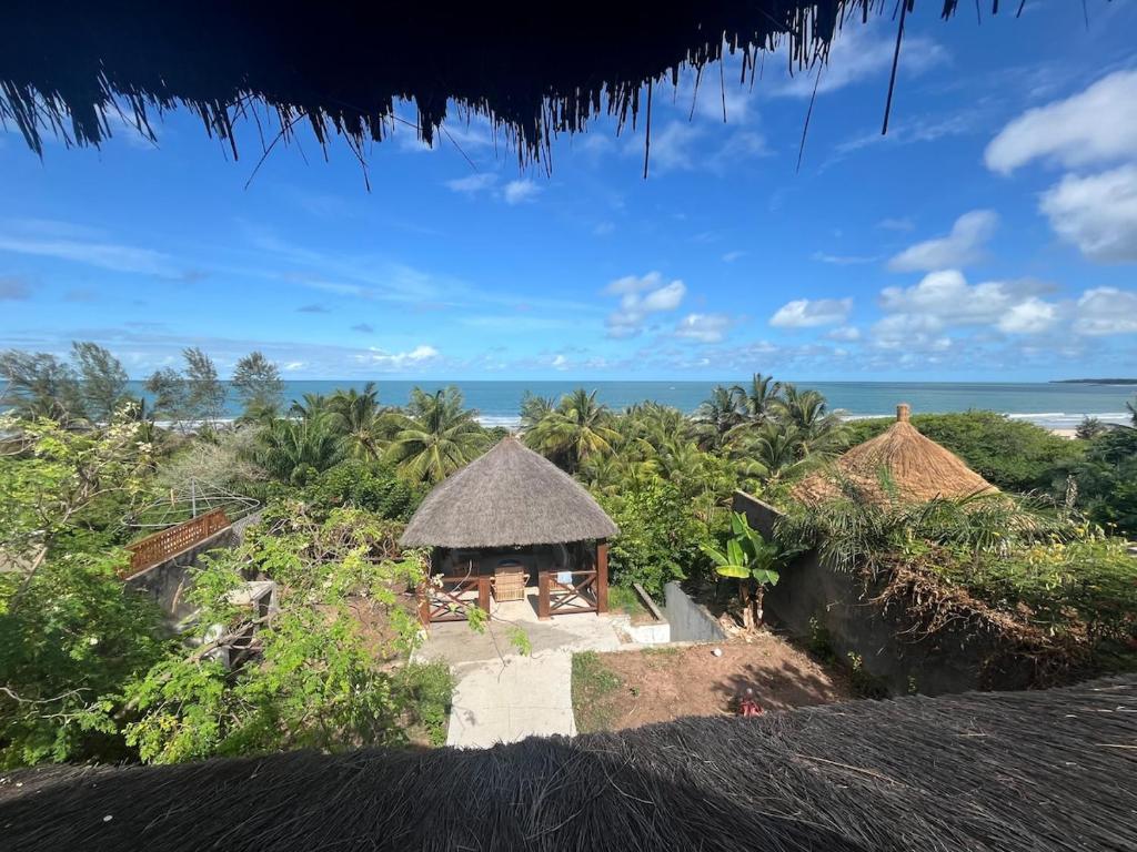 a group of huts with the ocean in the background at The Grove 1-4 bedroom beachfront villa in Cap Skirring