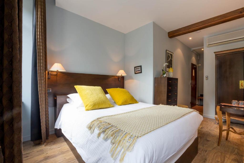 um quarto com uma cama grande e 2 almofadas amarelas em Les Chambres de L'Ecrit'Vin - En plein coeur du centre-ville em Beaune