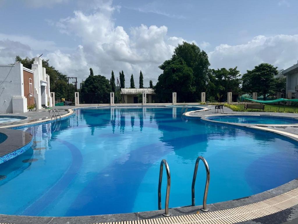 a large swimming pool with blue water at Viroha, Dahanu - Luxury 3BHK Farm Arvind Villa - 121 