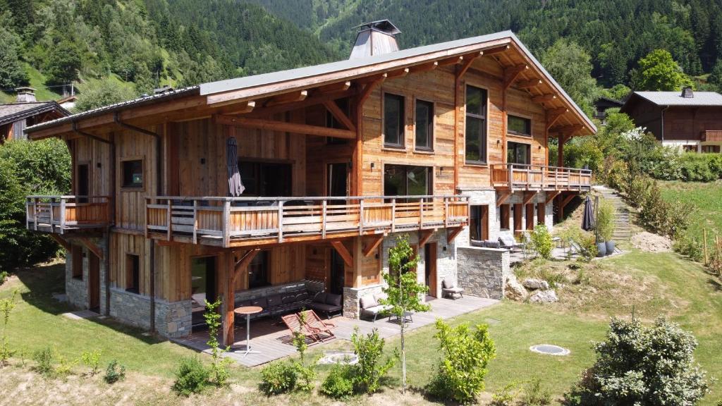una grande casa in legno con balcone su una collina di Magnifique chalet mitoyen - Jacuzzi - Cousinade II a Les Contamines-Montjoie