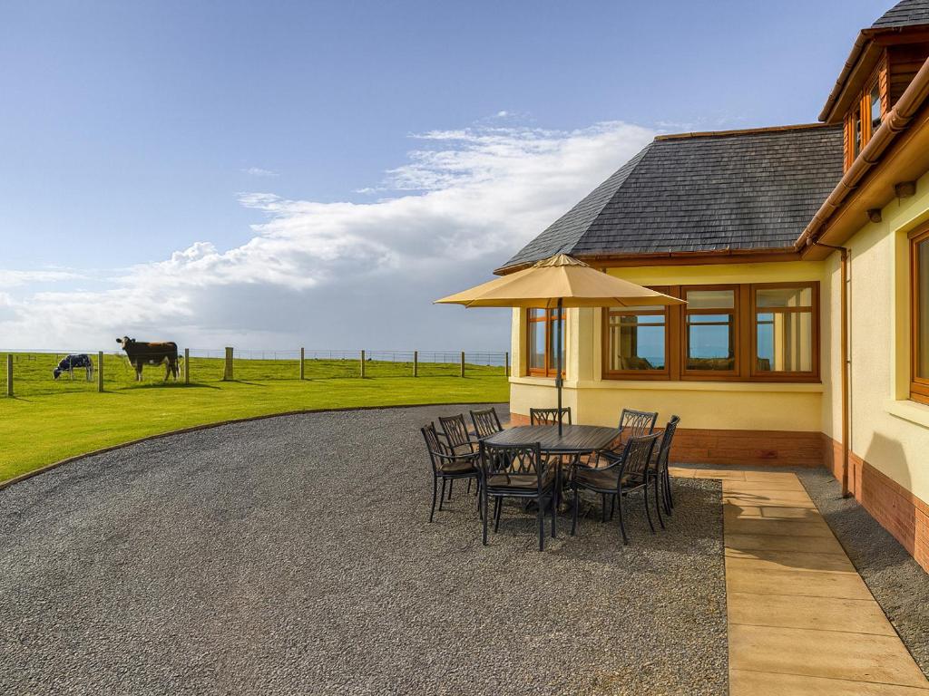 a patio with a table and chairs and a house at Corsewall Castle Farm Lodges in Kirkcolm