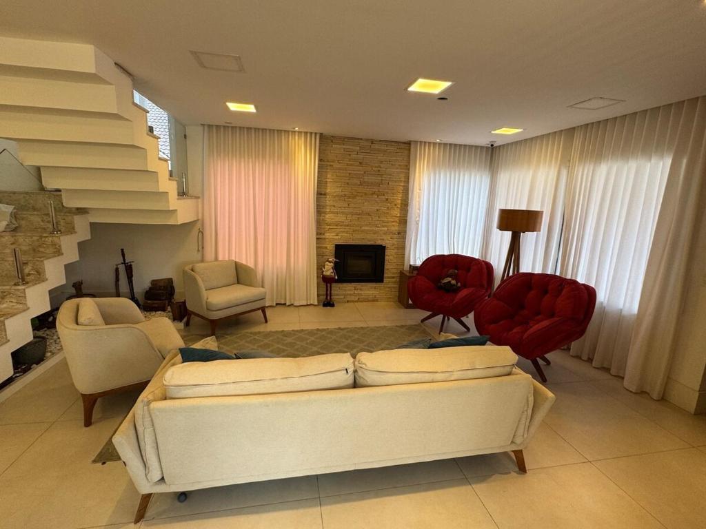 sala de estar con sofá blanco y sillas rojas en Casa do Vale em Gramado, en Gramado