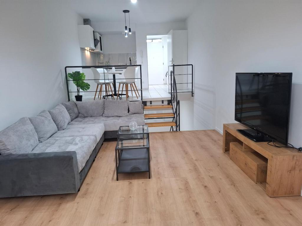 a living room with a gray couch and a television at Modern 2-room apartment with terrace in Gauting in Gauting