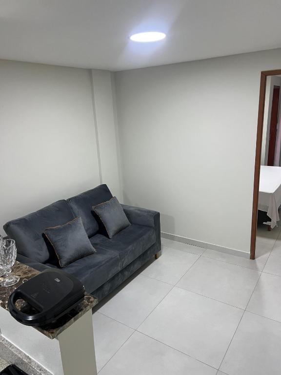 a black couch in a white room with a table at Edifício Flavan- Conforto e Estadia com Preços Acessíveis in Campos dos Goytacazes