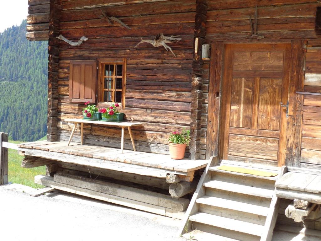 een houten hut met een trap, een deur en bloemen bij Tauhäusl in Innervillgraten