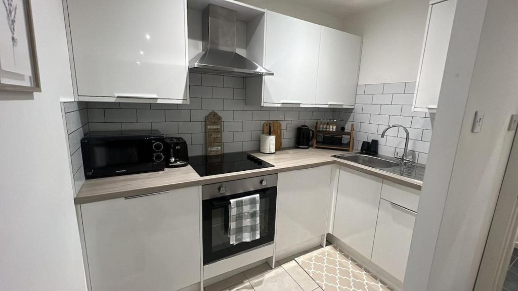 a kitchen with white cabinets and a black microwave at Chic & Comfy 1 Bed Apartment Sheffield Stay in Midland