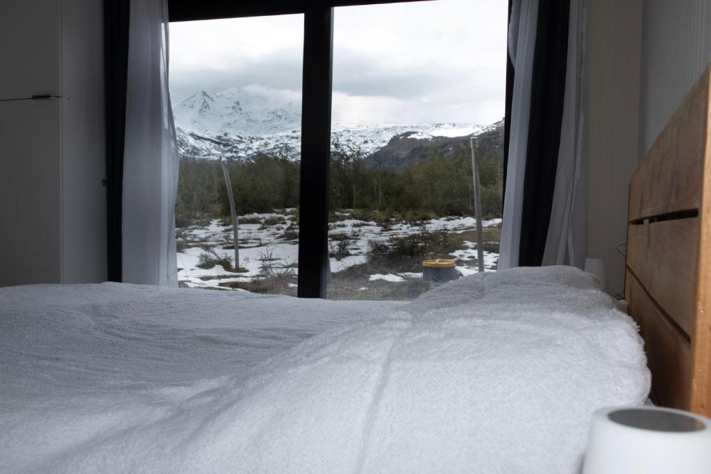 a bedroom with a bed and a window with snow covered mountains at Cabaña Vista ShangriLa, Las Trancas in Las Trancas