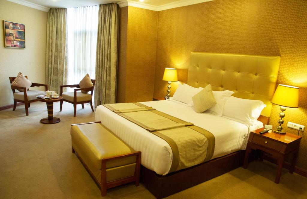 アディスアベバにあるジュピター インターナショナル ホテル カザンチスの大きなベッドと椅子が備わるホテルルームです。