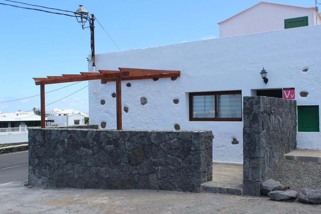 a white building with a stone wall in front of it at Casa Antonio-Tinajo in Tinajo