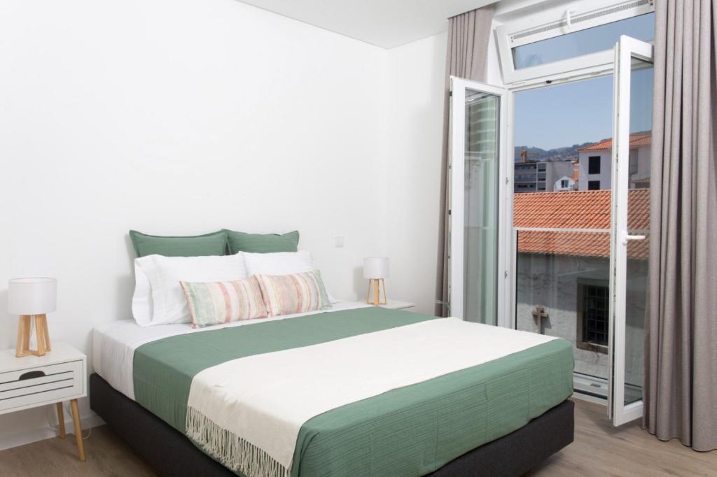 a bedroom with a bed and a large window at BJ Apartments Funchal in Funchal