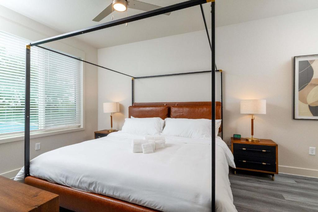 a bedroom with a canopy bed with white sheets at Trinity River - Skyline Views - King bed in Fort Worth