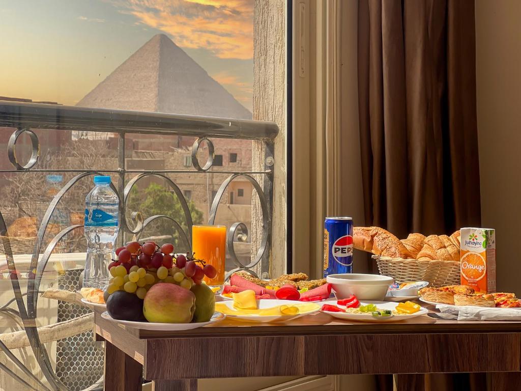 a table with food and a view of the pyramid at Hammis Pyramids View INN 7 Minutes from the New Grand Museum in Cairo