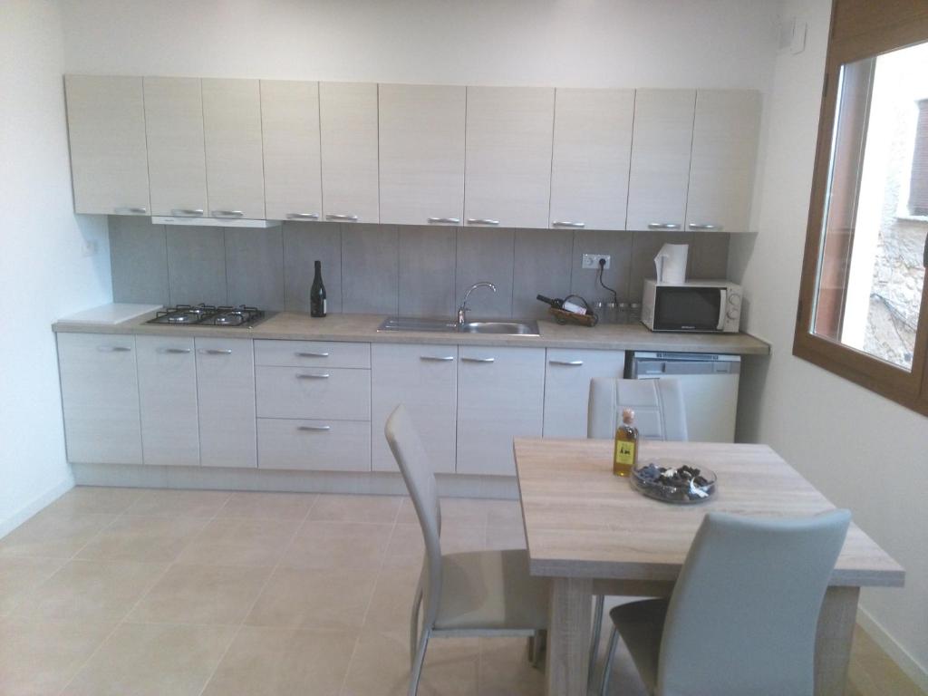 una cocina con armarios blancos y una mesa con sillas. en Cal Jordi, Fulleda, en Fulleda