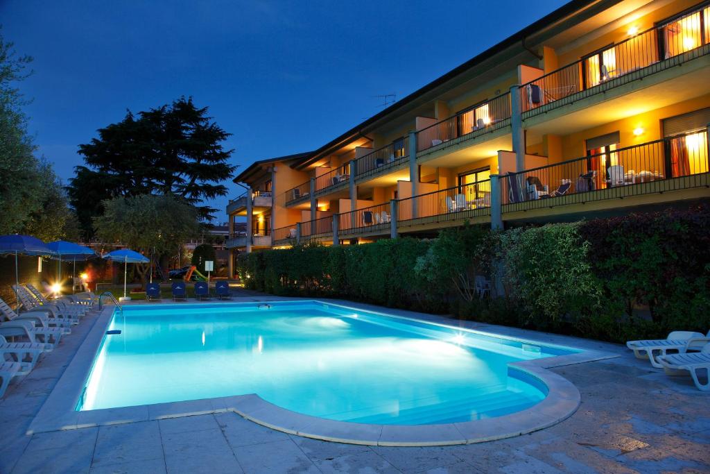 a swimming pool in front of a hotel at night at Residence Spiaggia D'Oro in Desenzano del Garda