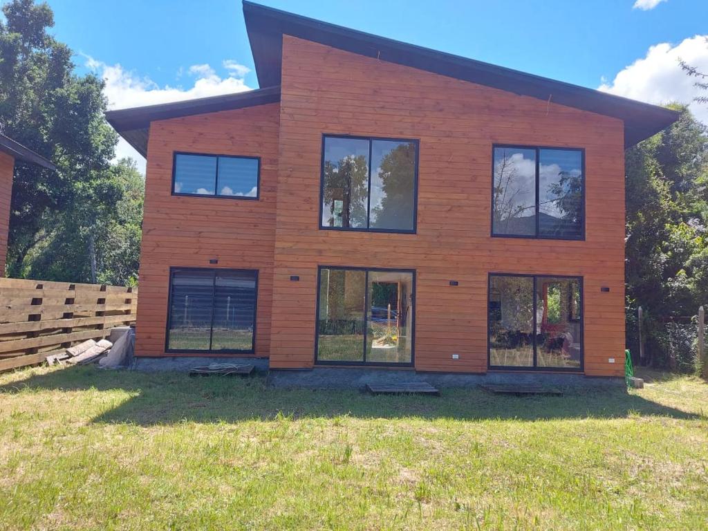 a house with windows on a grass field at Beautiful Cabin in Pucon 4D3B in El Cerrillo