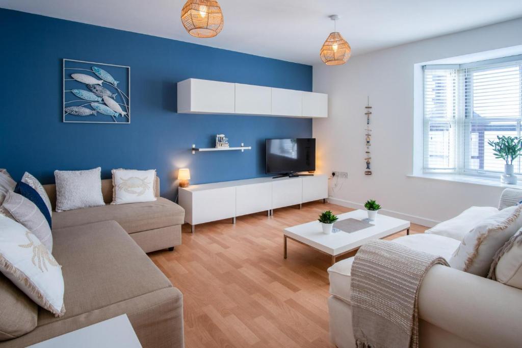 a living room with a couch and a tv at Windleshore - 2 Bedroom Apartment - Tenby in Tenby