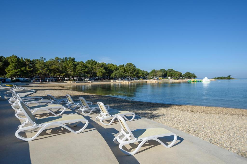 a row of chaise lounge chairs on a beach at Maistra Camping Valkanela Mobile homes in Funtana