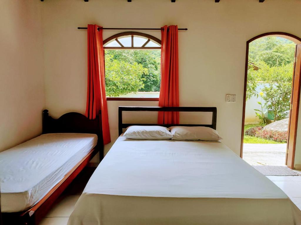 two beds in a room with a window at Pousada Canto Verde in Paraty