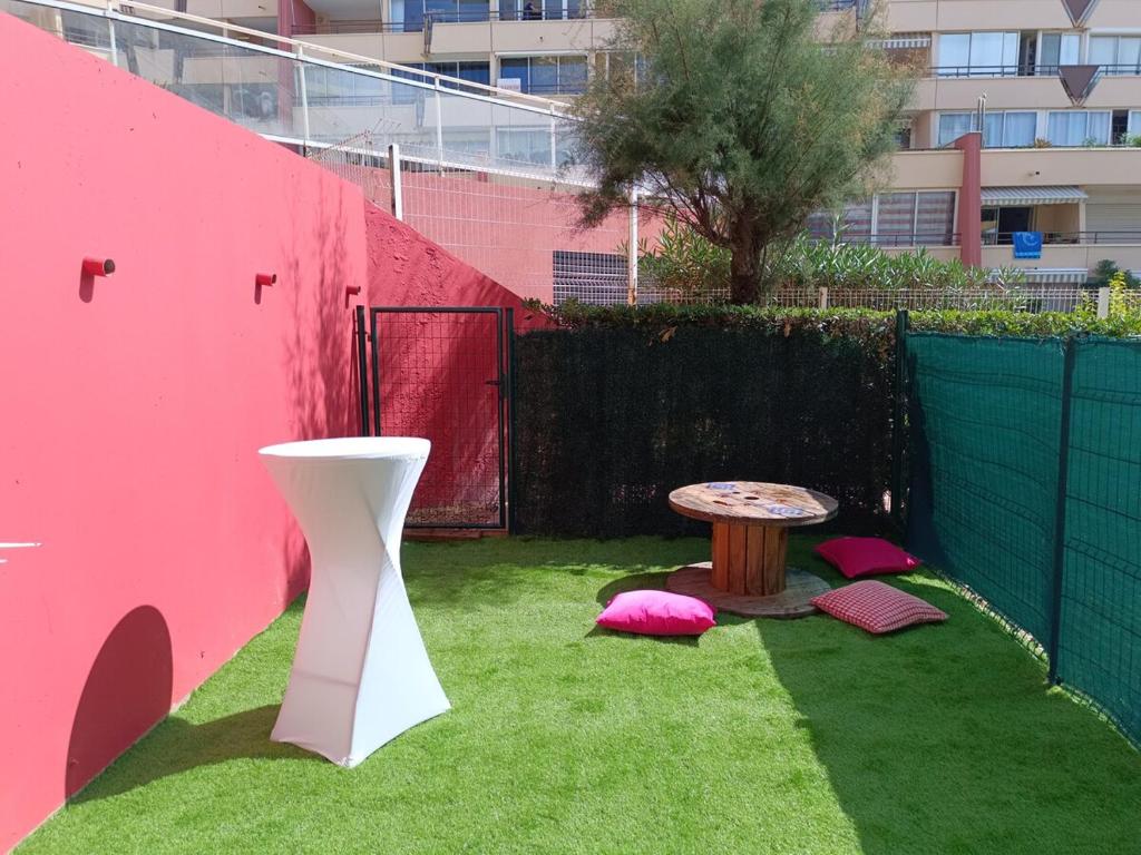 a small garden with a table and a pink wall at Beautiful apartment with direct beach access in Sète