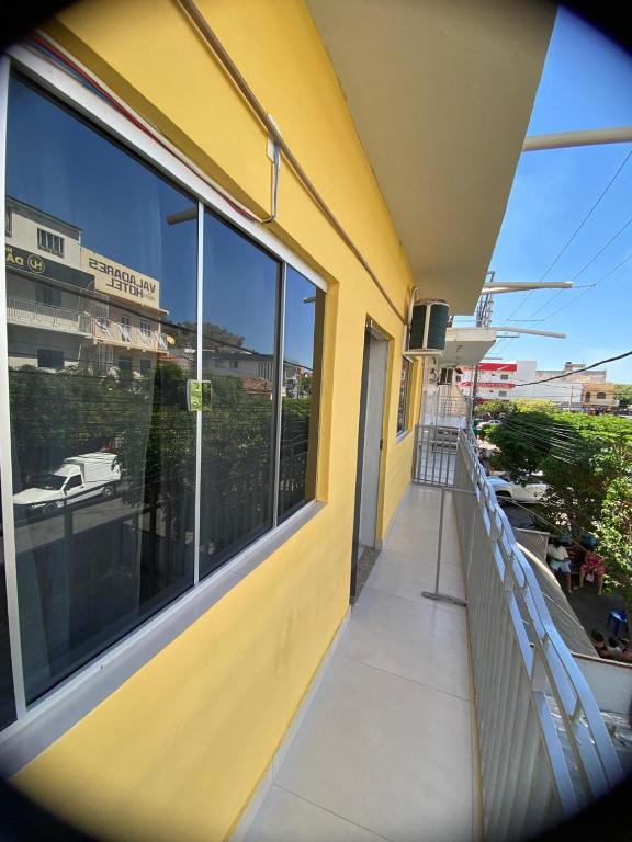 een geel gebouw met een balkon met een groot raam bij Dormitório Barreto in Bom Jesus da Lapa