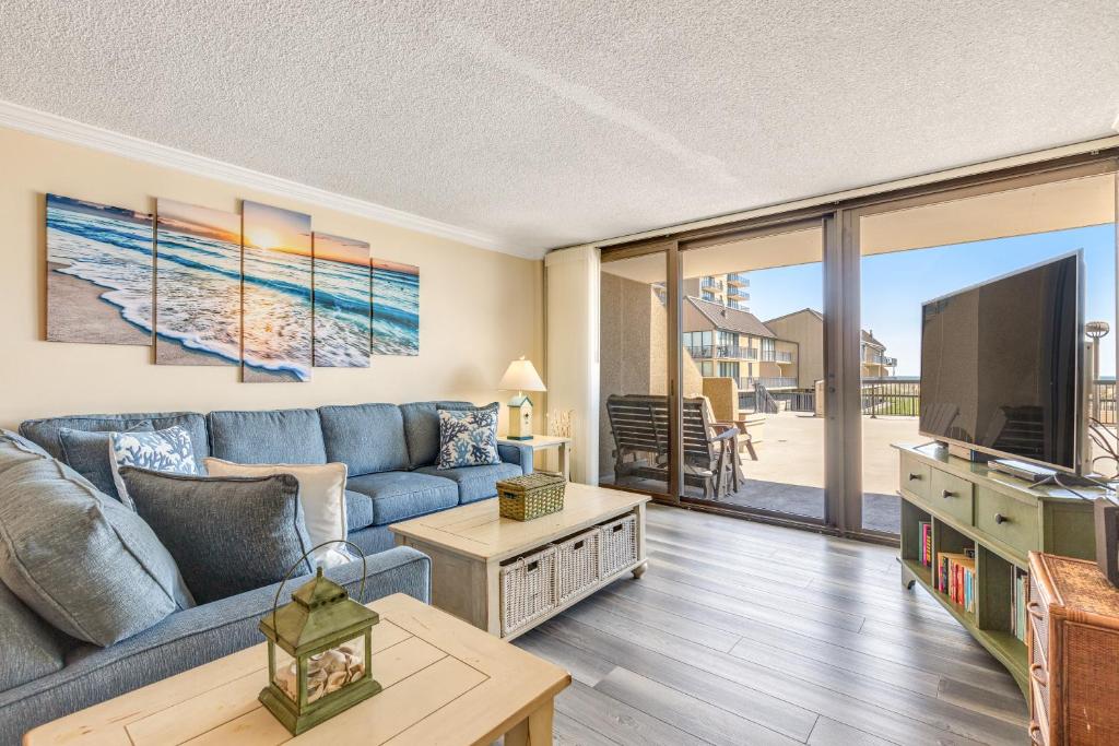 a living room with a blue couch and a tv at Sea Colony - 107 Chesapeake House Rd in Sea Colony