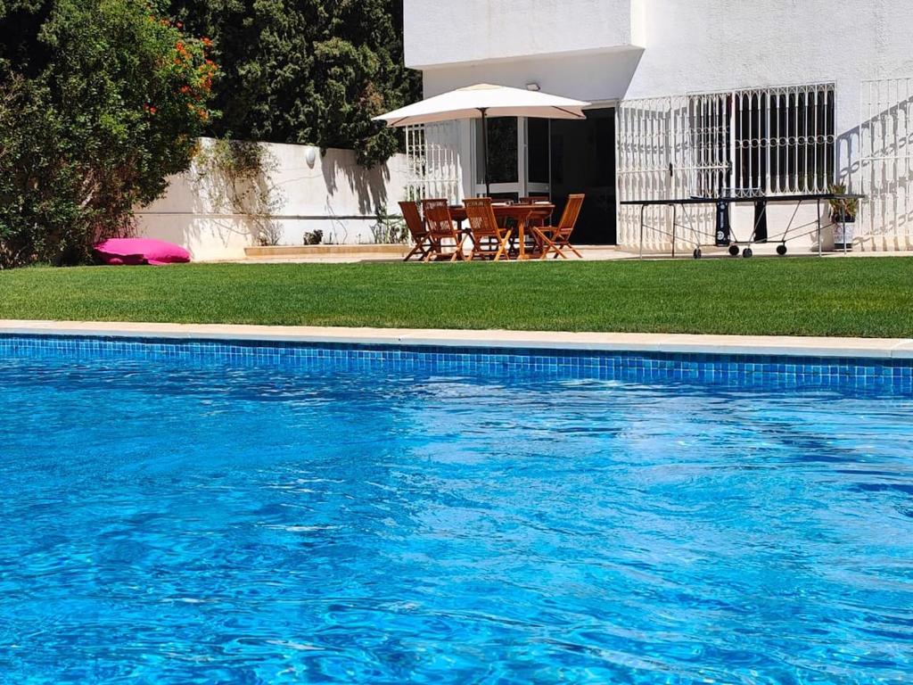une piscine avec une table et un parasol dans l'établissement Family villa in Hammamet pool - 10 min to beach, à Hammamet Sud