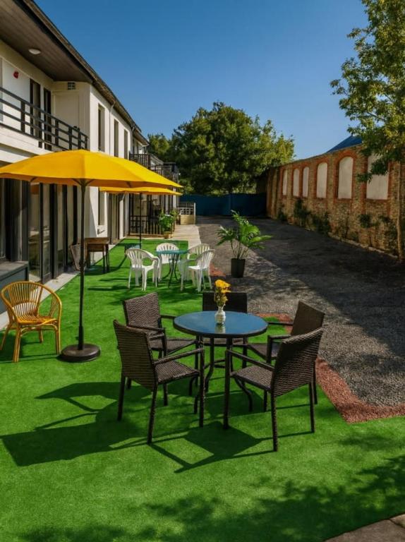a patio with tables and chairs and a yellow umbrella at Hotel La Baie Royale in Pontorson