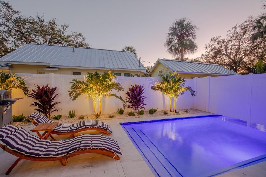 ein Swimmingpool mit zwei Stühlen und einem Haus in der Unterkunft Downtown-Gulfport-Cooled & Heated Pool in St Petersburg