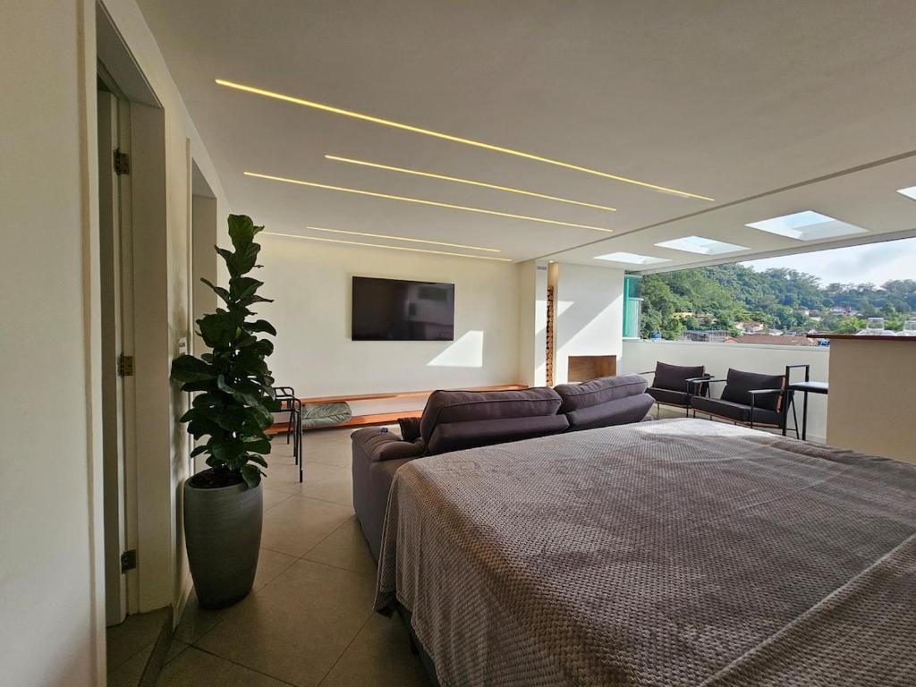 a bedroom with a bed and a couch and a tv at Cobertura Elegância da Serra in Petrópolis