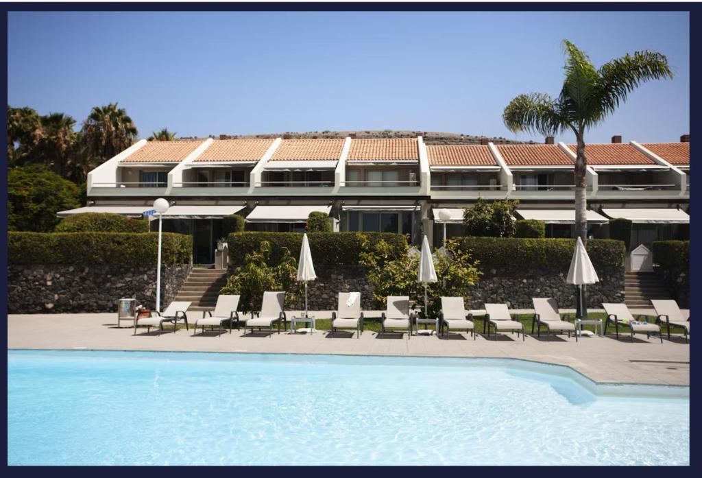 a resort with a swimming pool and chairs and a building at Relax Blue Marlin Pasito Blanco in Pasito Blanco
