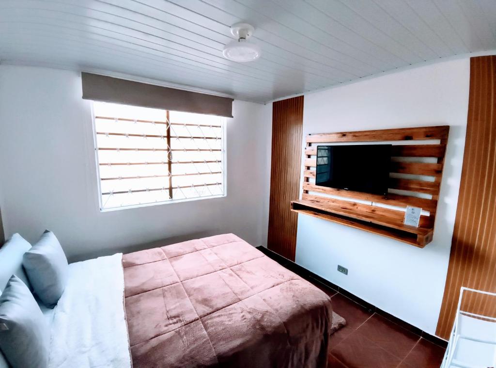 a bedroom with a bed and a flat screen tv at Suíte Nosso Abrigo - Jaguaribe 2km do Capivari in Campos do Jordão