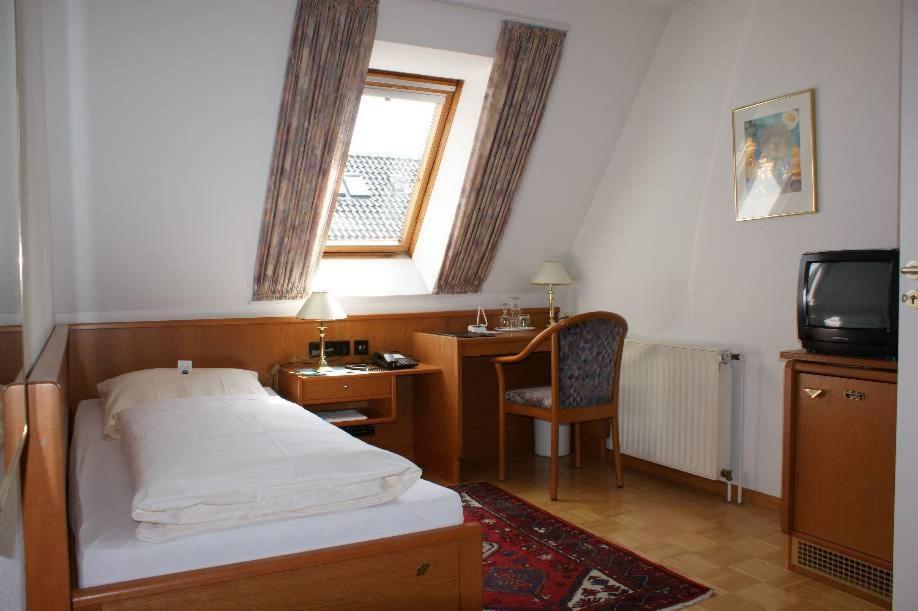 a bedroom with a bed and a desk and a television at Altstadt Hotel Meppen in Meppen