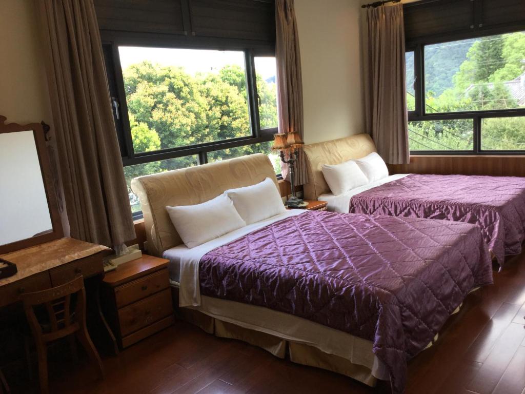 a bedroom with two beds and large windows at 闕麒景觀民宿Chill Villa B&amp;B in Puli