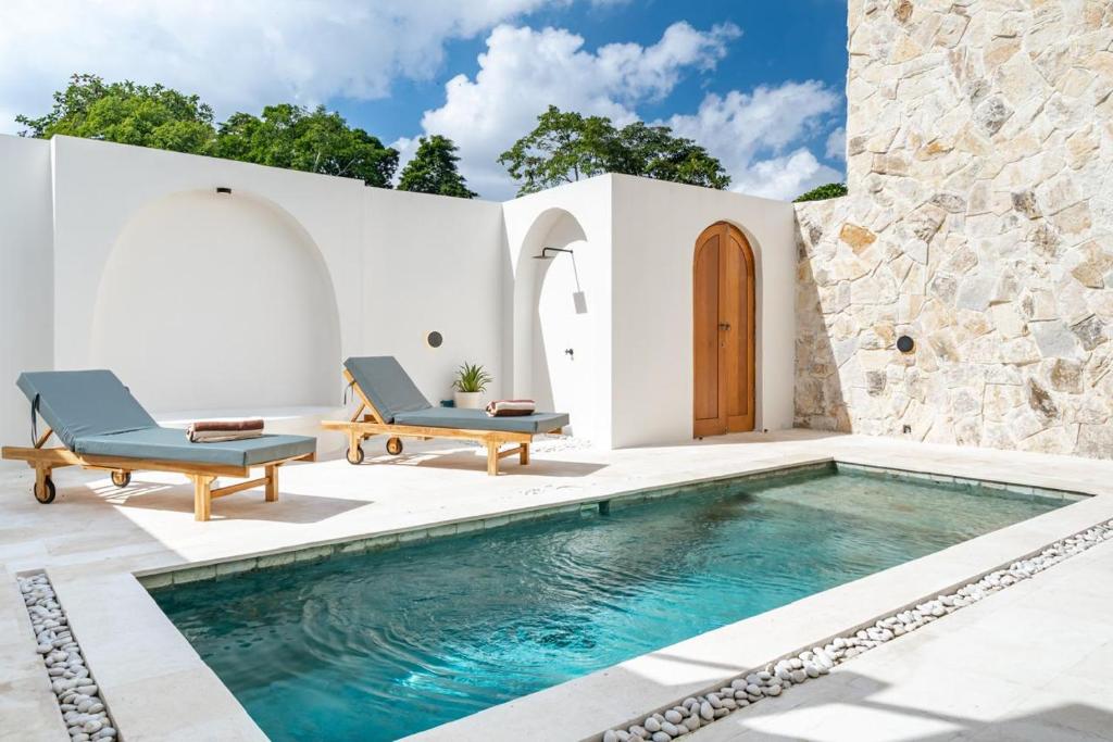 a pool in the backyard of a house with two blue chairs at Chezfred Villa, Pererenan,Tumbak Bayuh in Tumbak Bayuh