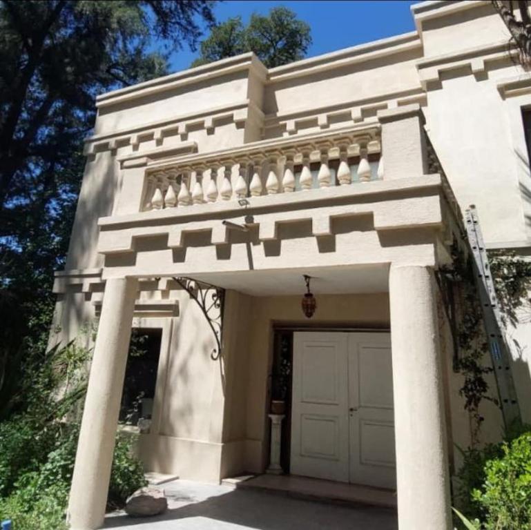 a white house with a gate and a garage at Casa quinta con jardín y pileta in Luján