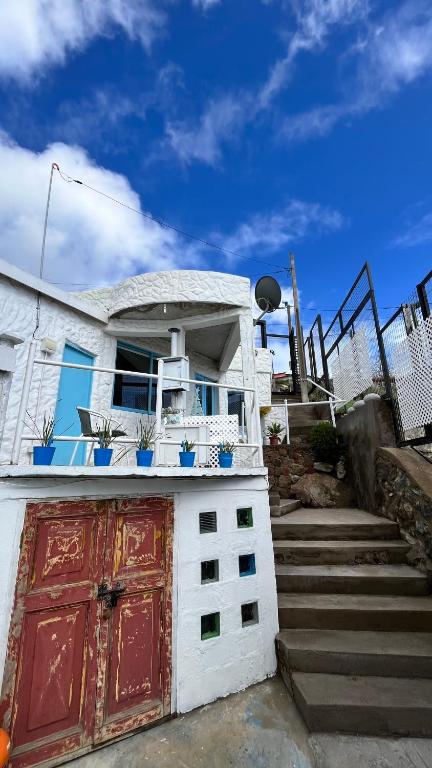 a white house with a red door and some stairs at My little Santorini in Guanaqueros