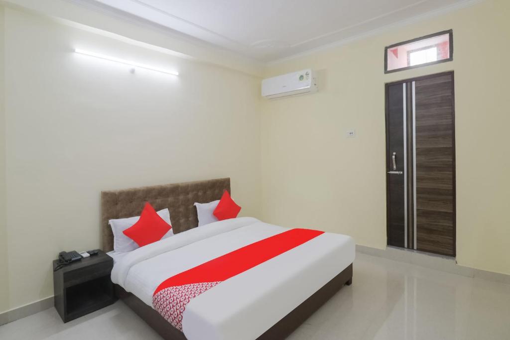 Un dormitorio con una gran cama blanca con almohadas rojas. en Super HOTEL O R.K. INN, en Gorakhpur