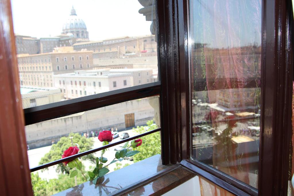 ローマにあるLe Bellezze Vaticaneの赤いバラが咲く街の景色を望む窓