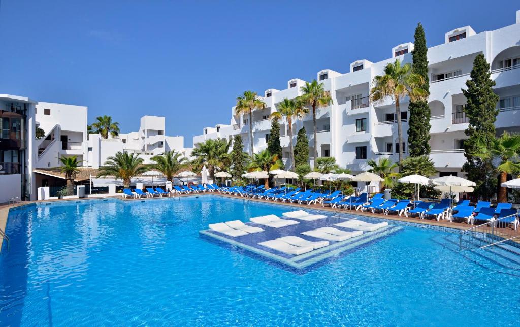 a large swimming pool with lounge chairs and umbrellas at Sol Cala d´Or Apartamentos in Cala d´Or