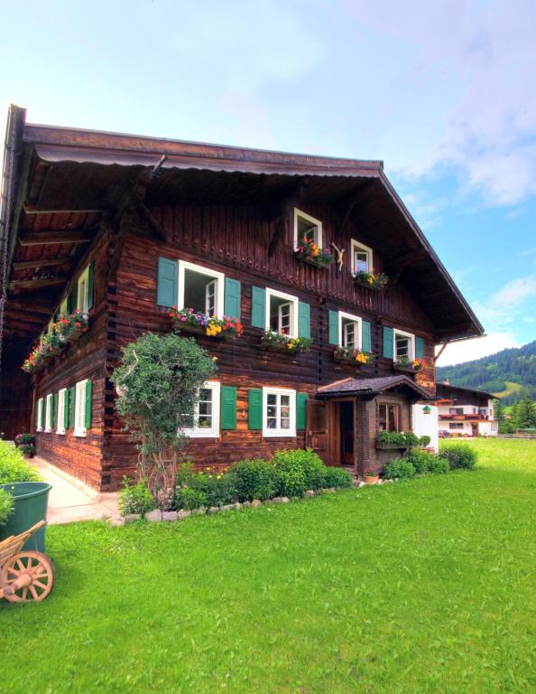 a wooden house with flowers on the front of it at Tirolerhaus Tannheim - zentral und ruhig - gemütliche Dachgeschosswohnung mit separater Küche, Schlafzimmer & Charme - ab 7 Tage buchbar in Tannheim