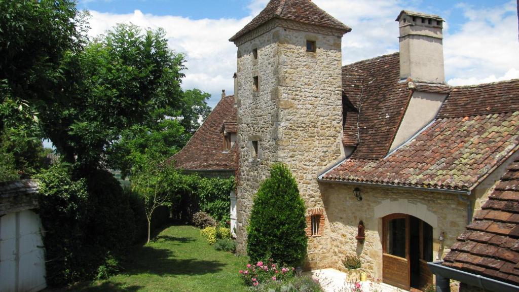 um antigo edifício de pedra com uma torre num quintal em Manoir de Rieuzal em Loubressac