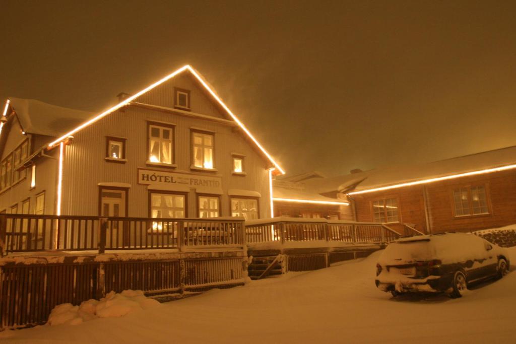 a house with a car parked in the snow at night at Hotel Framtid in Djúpivogur