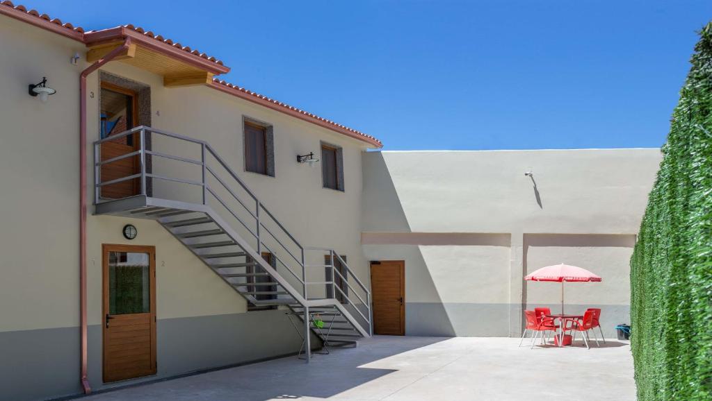 una escalera que conduce a un edificio con una mesa y una sombrilla en Pensión Pereiro, en Melide