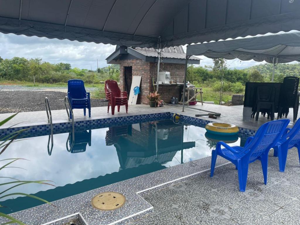 チャンルーンにあるVilla Cempaka Homestayの椅子とパラソルのあるプール